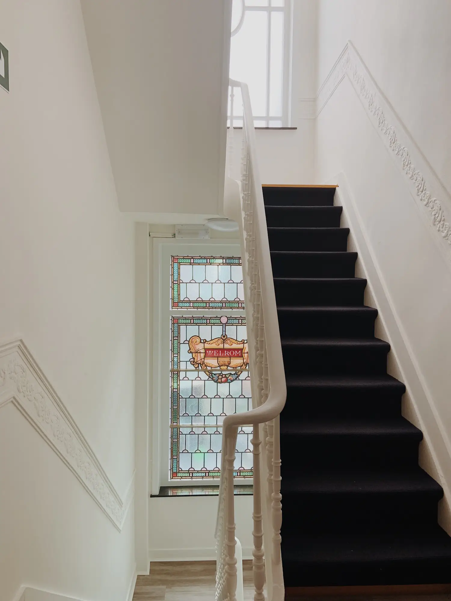 Historic staircase with welcoming stained glass at La Lys