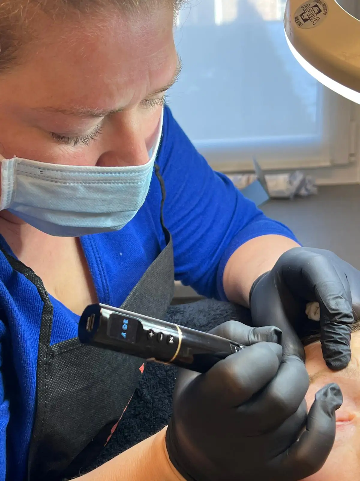 Davina voert geconcentreerd een powder brows behandeling uit met handapparaat