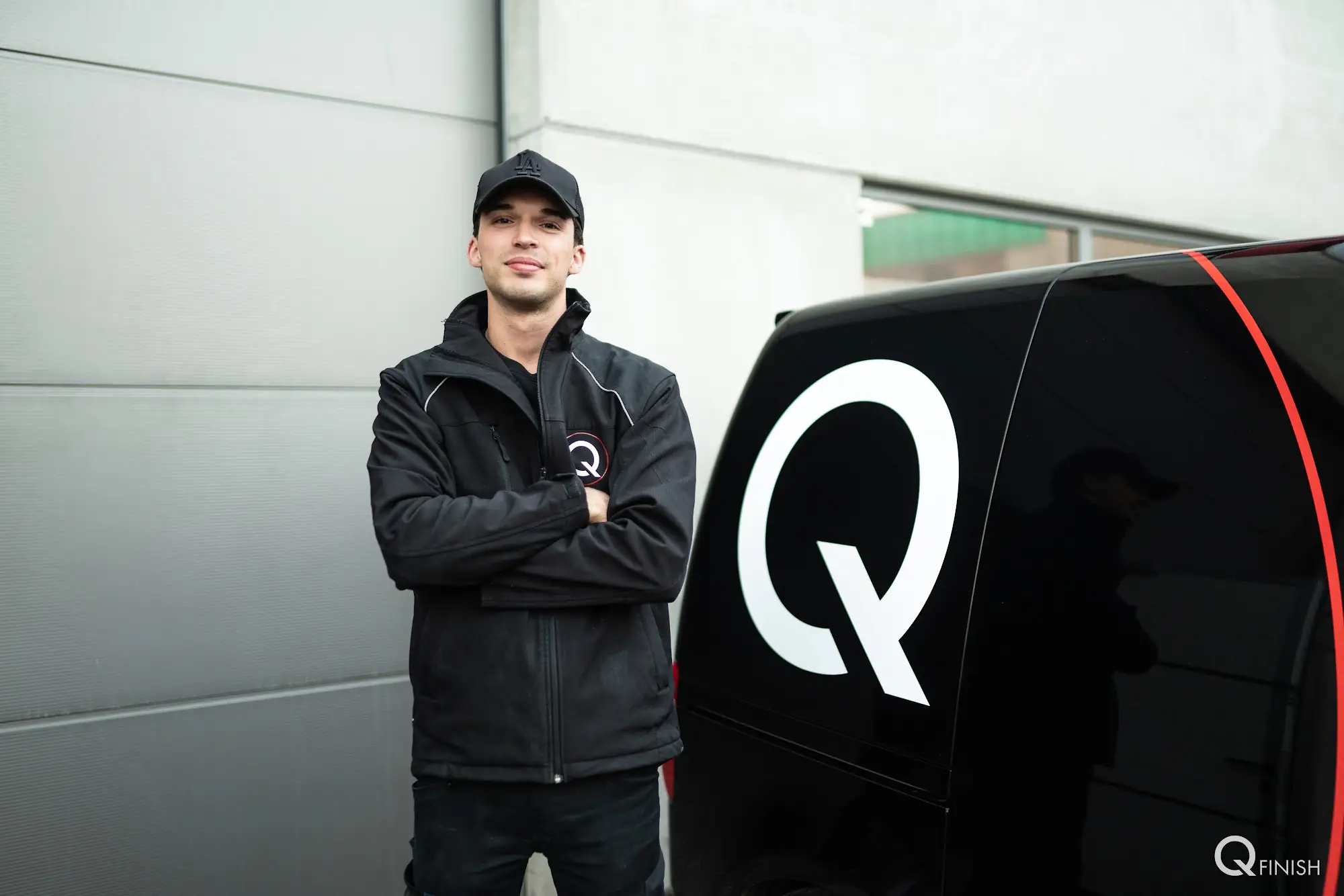 QFINISH technicus naast zwarte bestelwagen met wit Q-logo