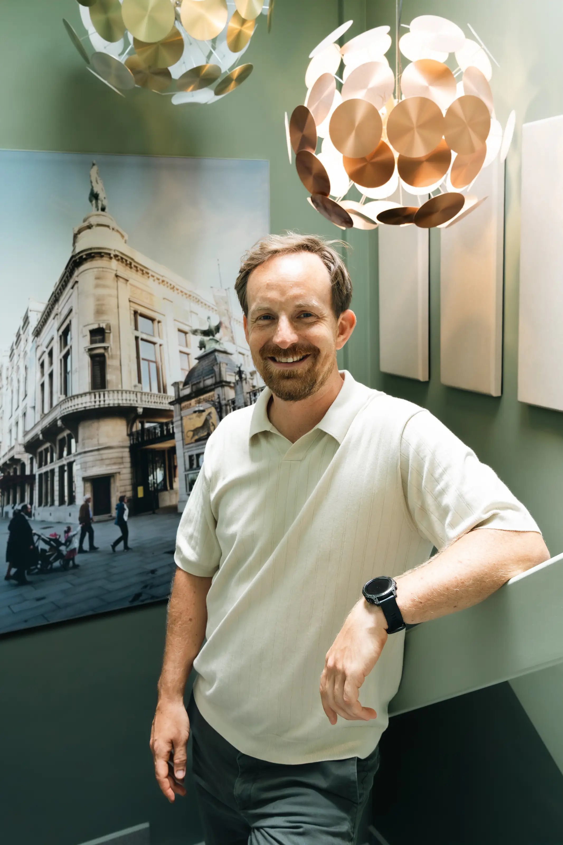 Tobias leunt glimlachend tegen een balustrade in het interieur van zijn hotel