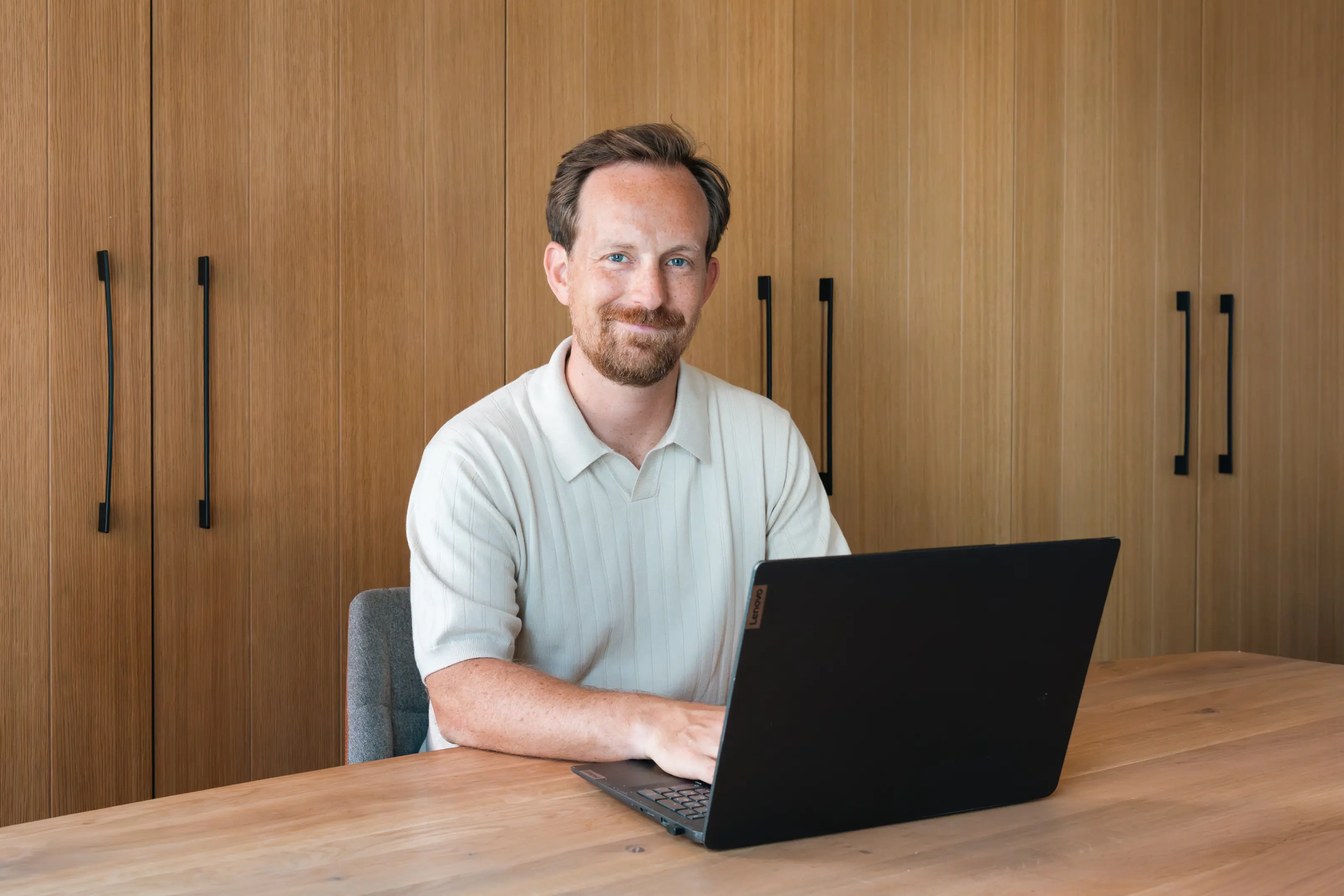 Tobias werkt aan zijn laptop aan een houten bureau in het hotel