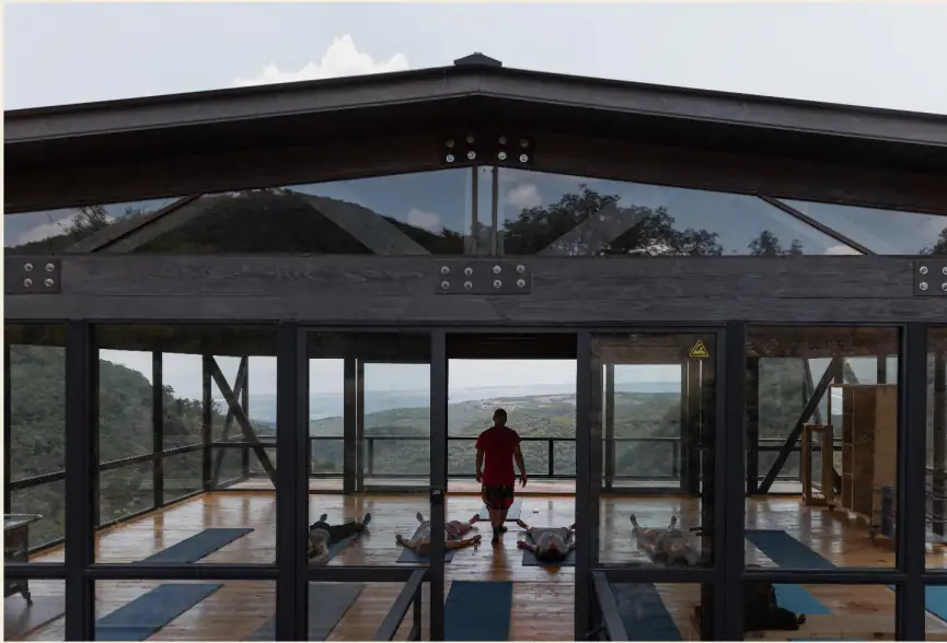 Групповая практика йоги в стеклянной студии с видом на природу