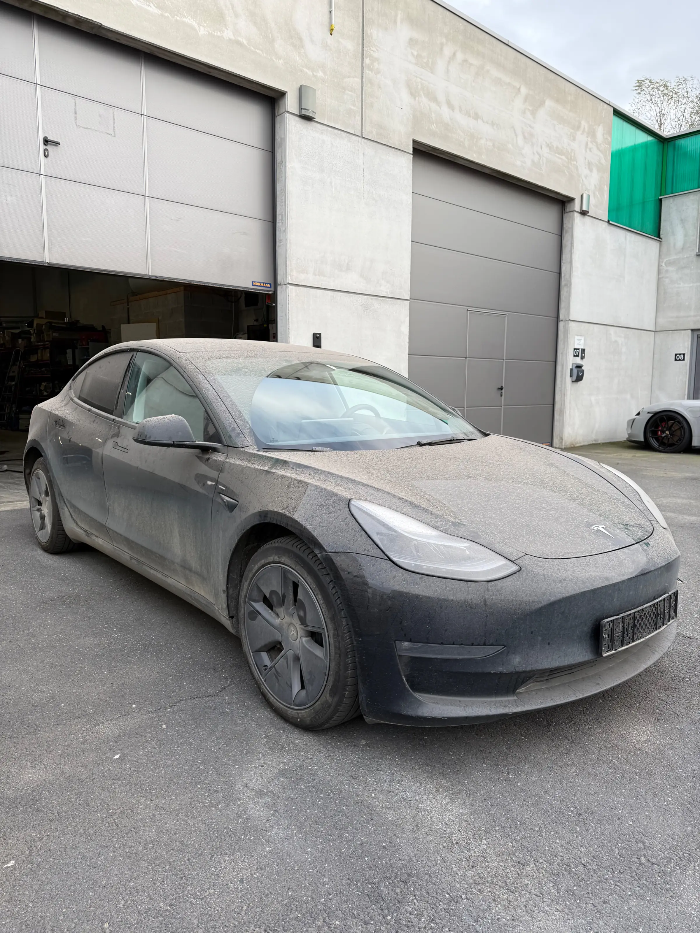 Zwarte Tesla Model 3 voor industriële poort