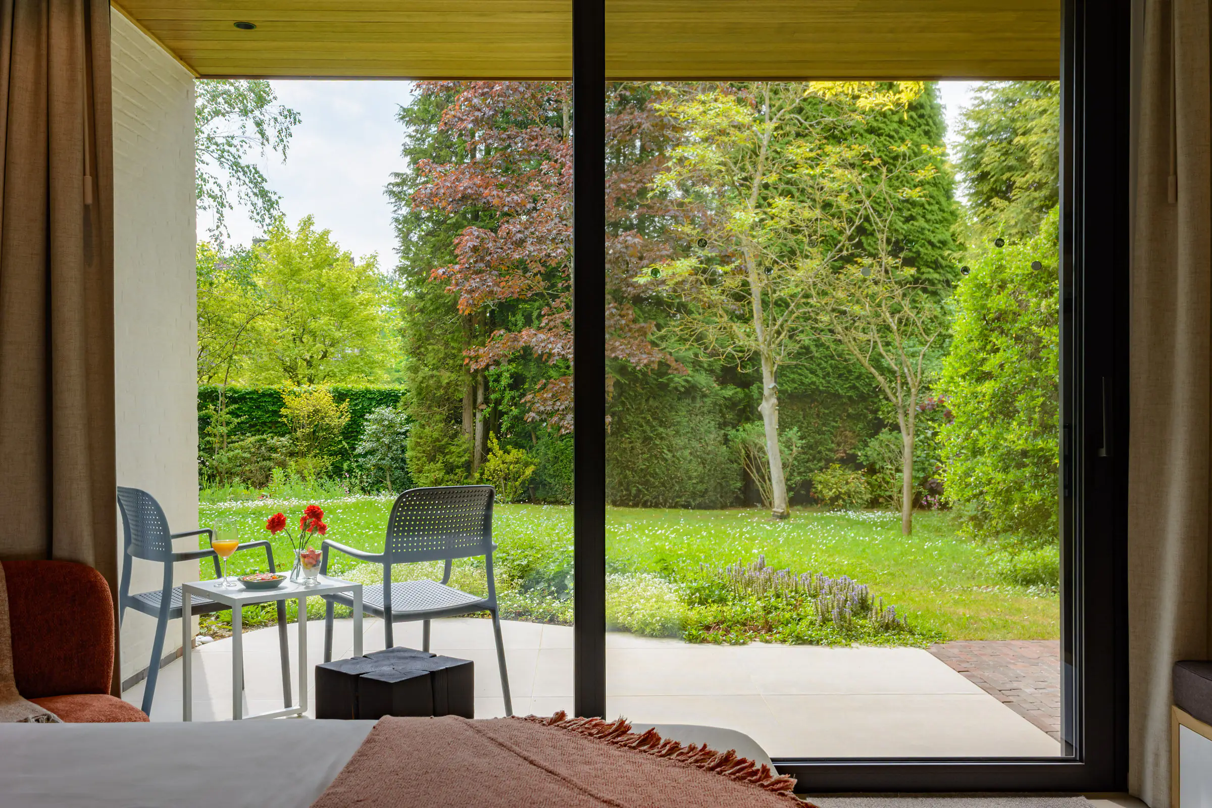 Het uitzicht vanuit de kamer door de glazen schuifdeur naar het zonnige terras