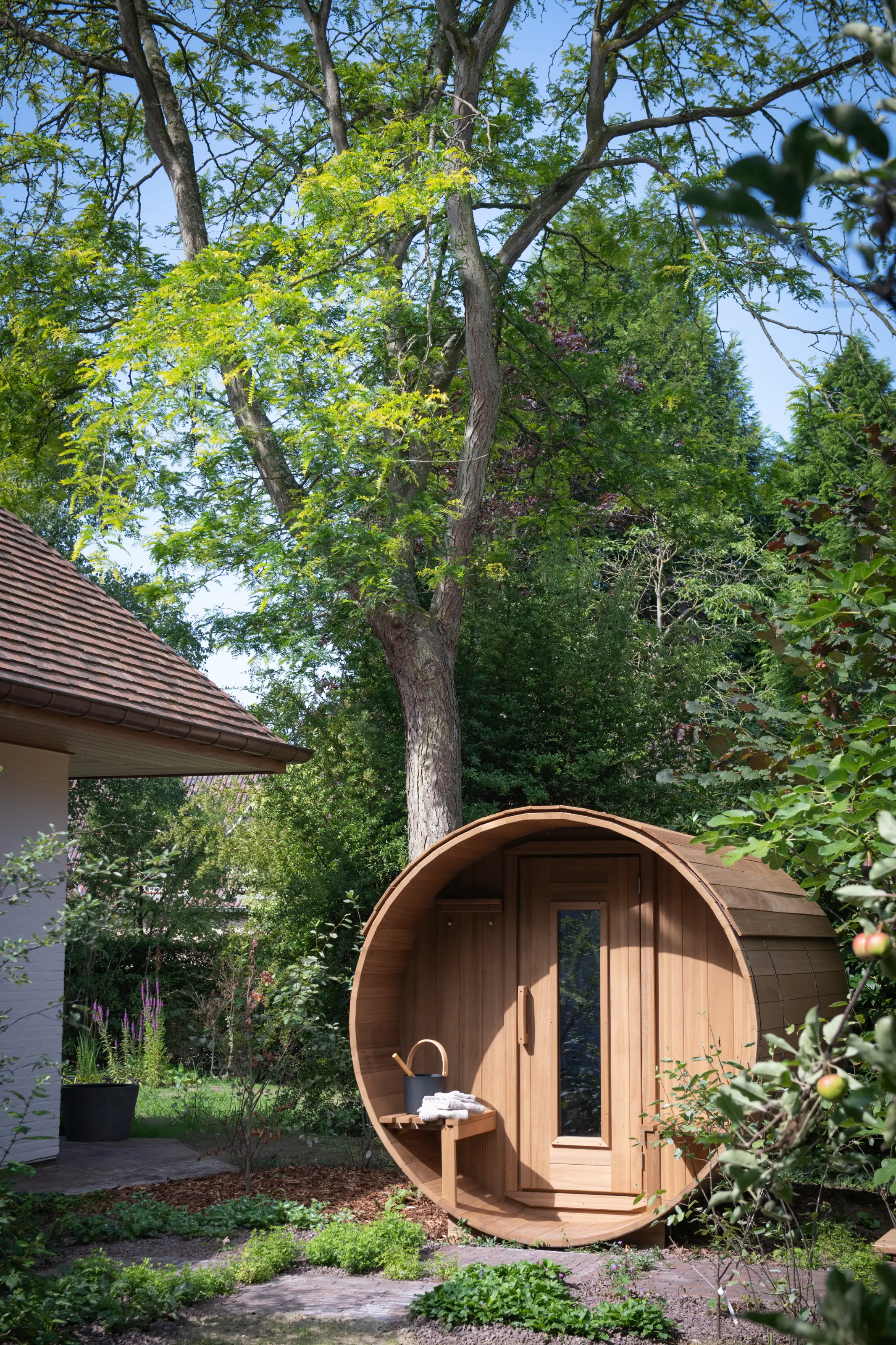 Houten tonsauna in de weelderige tuin