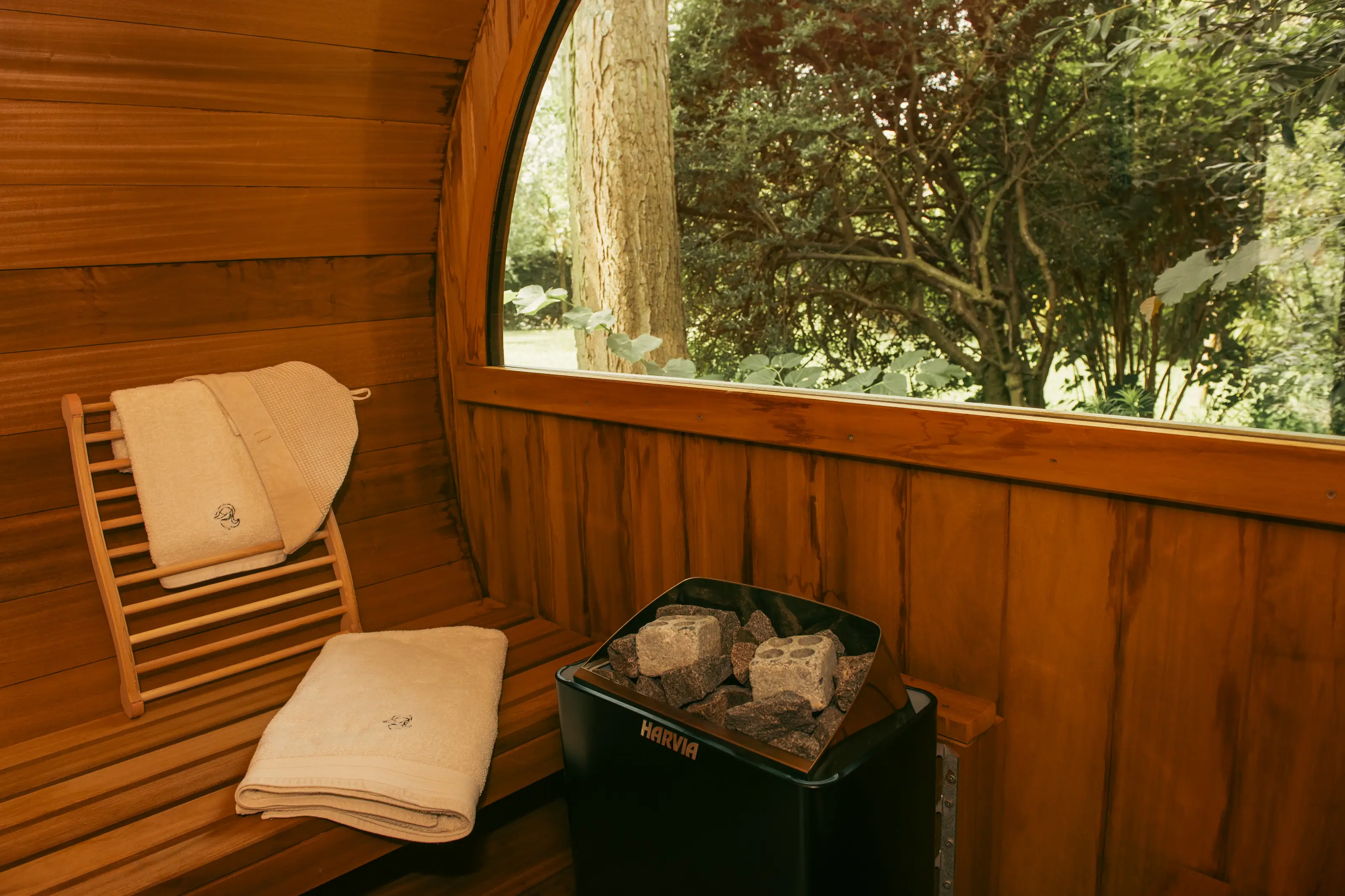 Interieur van de tonsauna met Harvia kachel en tuinzicht