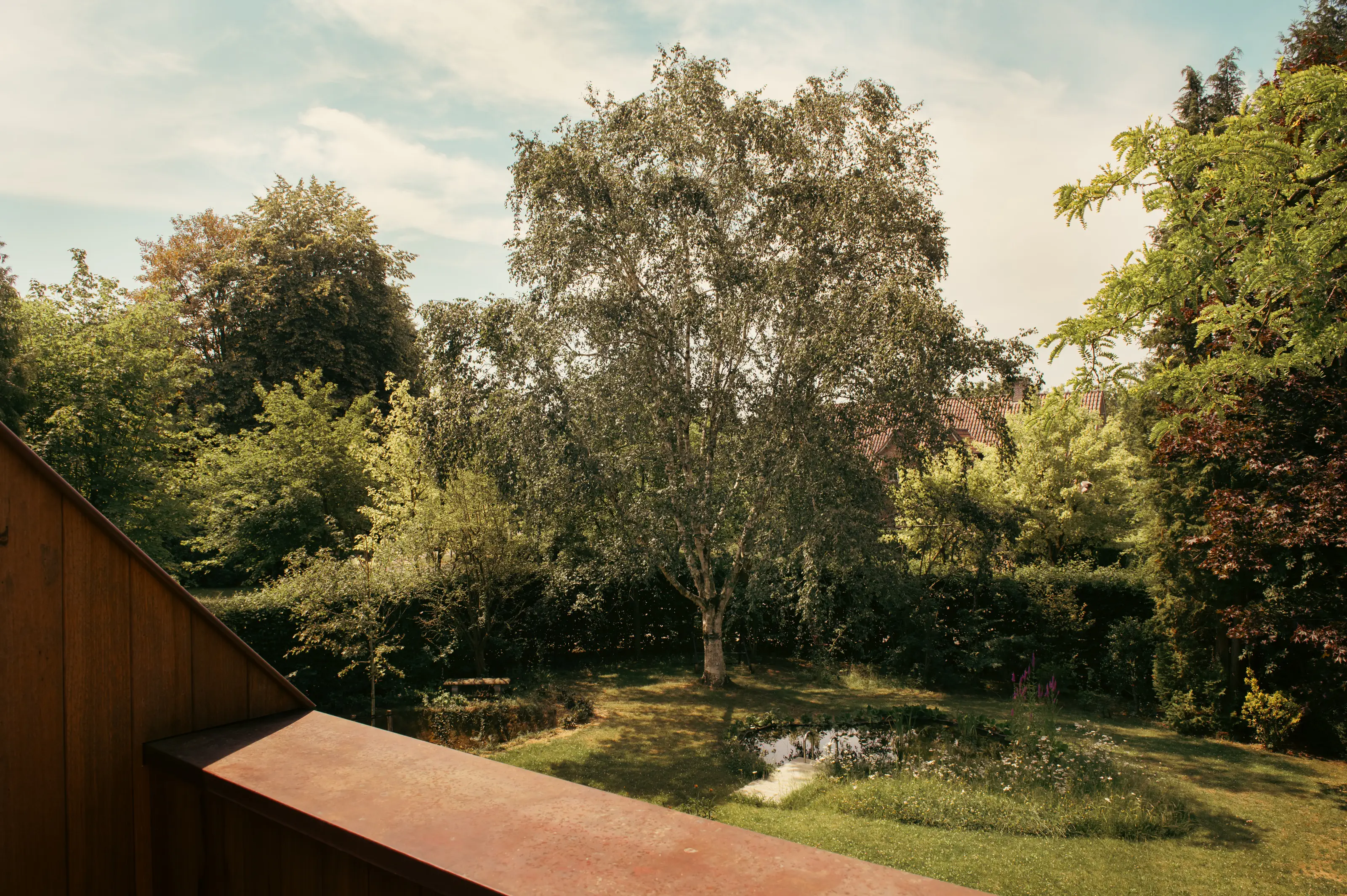 Zicht op de groene tuin met vijver vanuit de kamer
