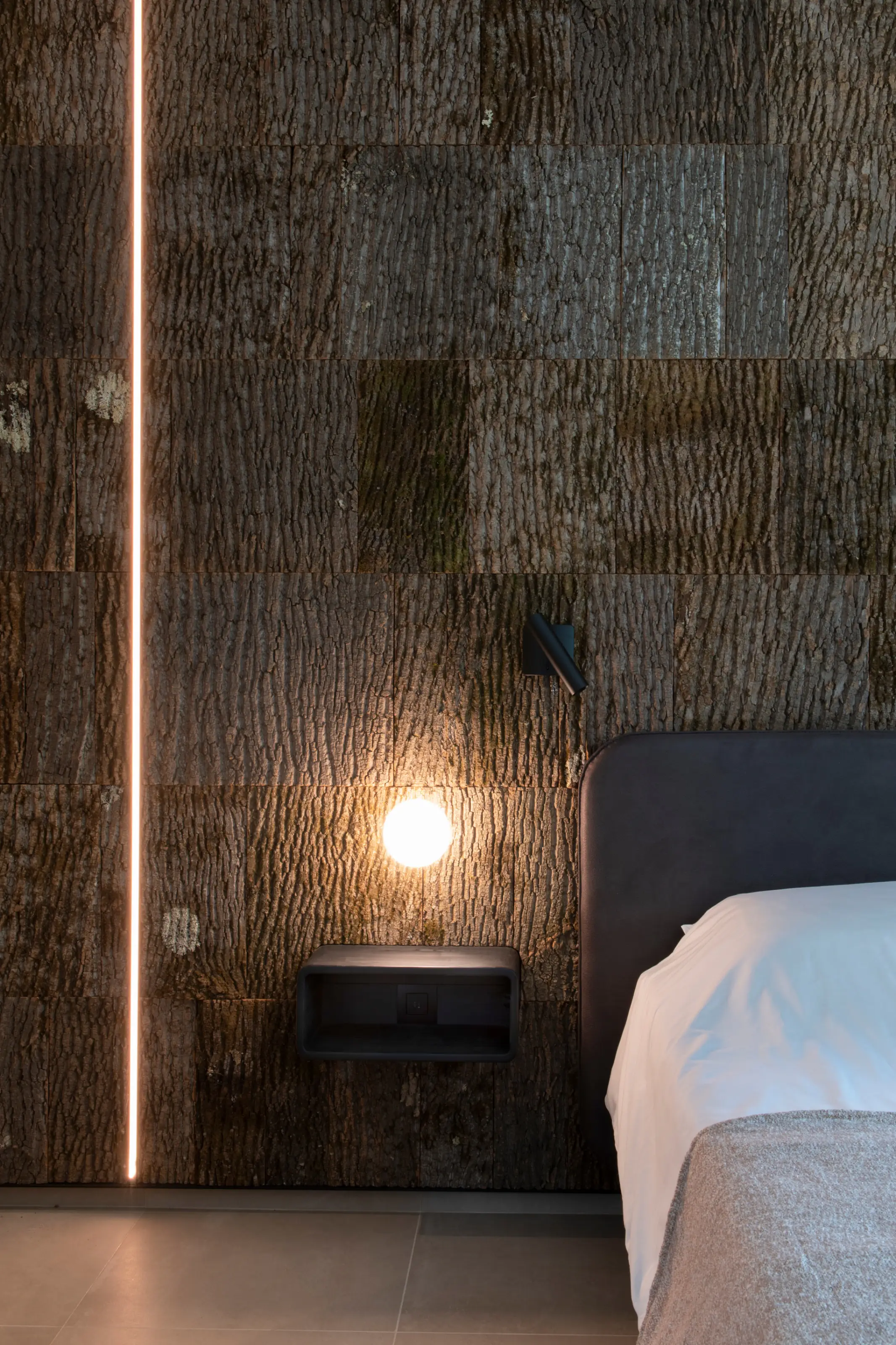 Slaapkamer detail met donkere schorswand en sfeerlamp
