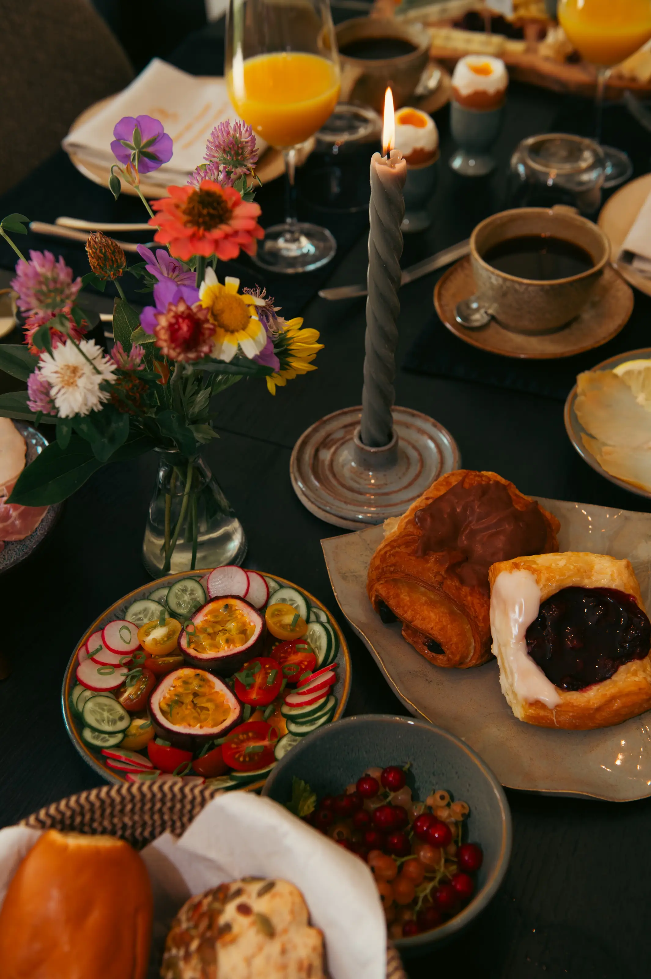Rijkelijk gedekte ontbijttafel met verse streekproducten, fruit, broodjes en bloemen