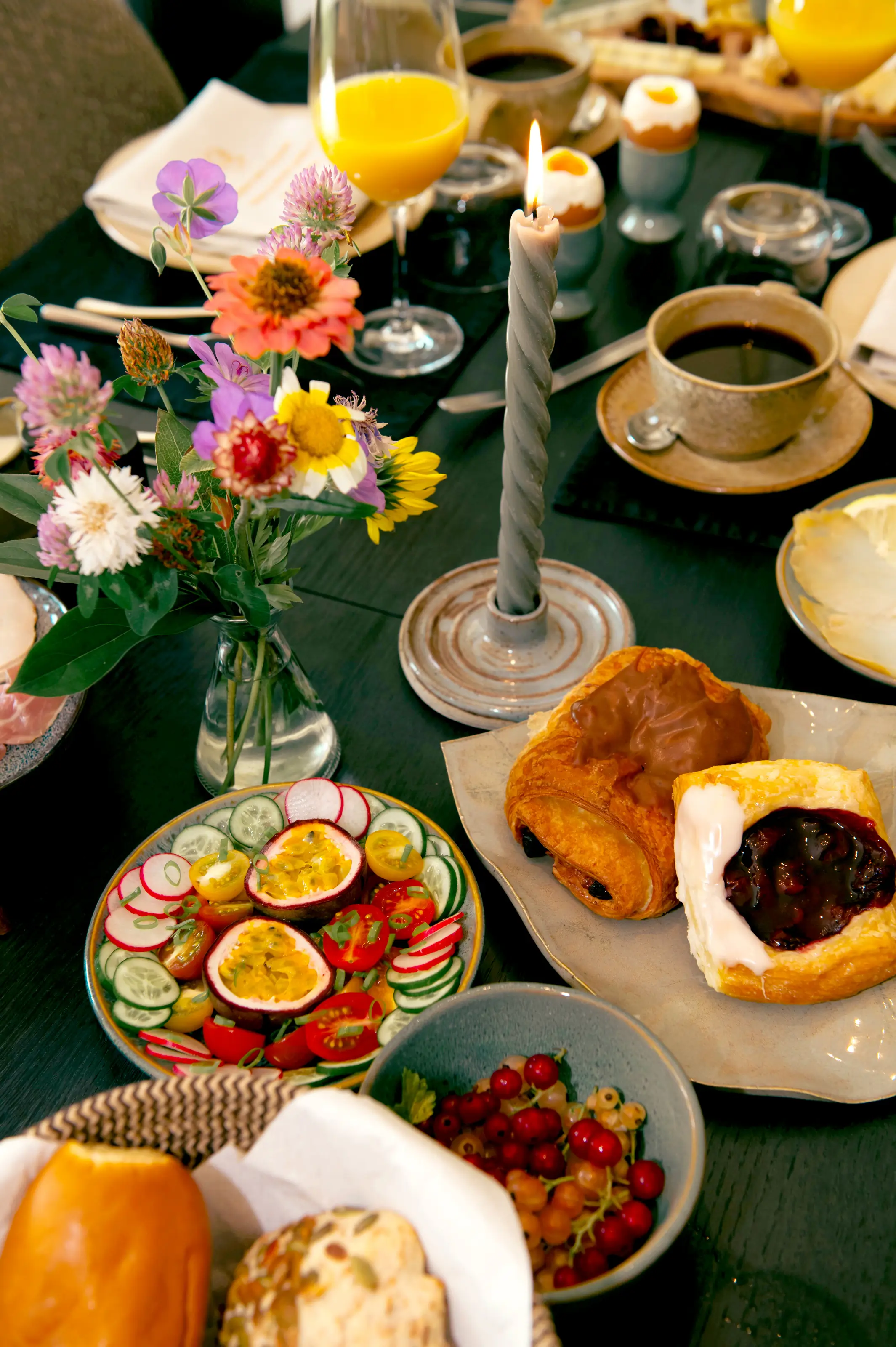Rijkelijk gedekte ontbijttafel met verse streekproducten, fruit, broodjes en bloemen